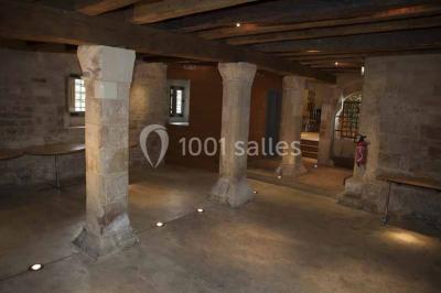 Un bâtiment en pierre avec un toit en tuiles rouges, entouré de jardins fleuris, accueille un groupe de personnes.