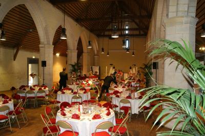 Un bâtiment en pierre avec un toit en tuiles rouges, entouré de jardins fleuris, accueille un groupe de personnes.