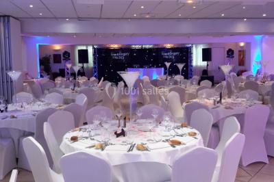 Buffet en extérieur avec tables garnies de plats, invités debout discutant sous des parasols blancs.