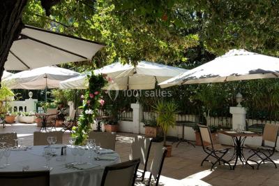 Buffet en extérieur avec tables garnies de plats, invités debout discutant sous des parasols blancs.