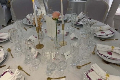 Buffet en extérieur avec tables garnies de plats, invités debout discutant sous des parasols blancs.