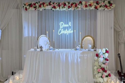 Buffet en extérieur avec tables garnies de plats, invités debout discutant sous des parasols blancs.
