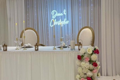Buffet en extérieur avec tables garnies de plats, invités debout discutant sous des parasols blancs.