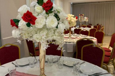 Buffet en extérieur avec tables garnies de plats, invités debout discutant sous des parasols blancs.