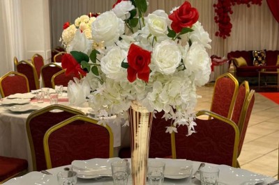 Buffet en extérieur avec tables garnies de plats, invités debout discutant sous des parasols blancs.