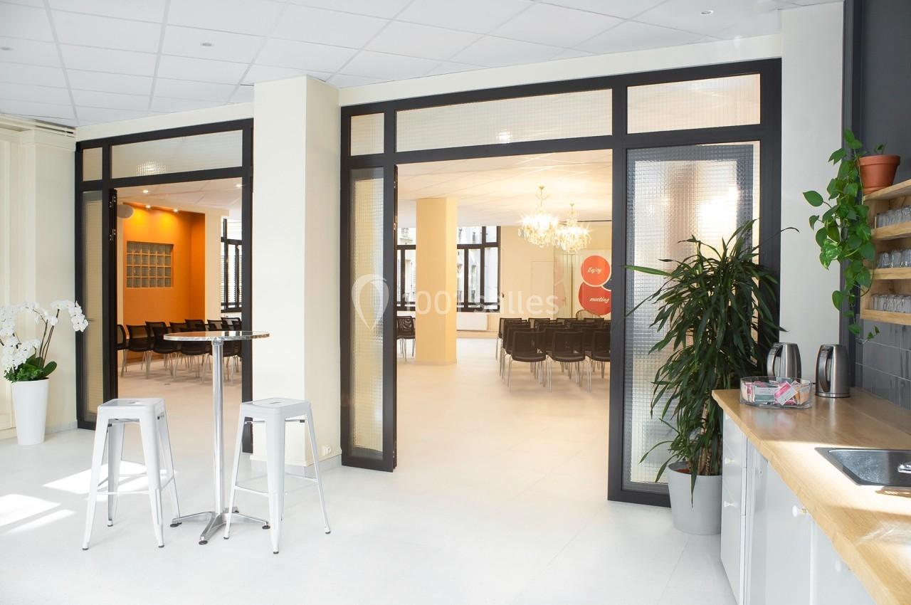 Espace lumineux avec chaises alignées, plantes, comptoir et tabourets dans un intérieur moderne et épuré.