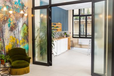 Salle de réunion lumineuse avec tables alignées, chaises noires, bouteilles d'eau et étagères en arrière-plan.