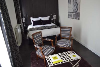 Chambre avec lit double, deux fauteuils rayés, table basse blanche et décoration murale dans un intérieur moderne.