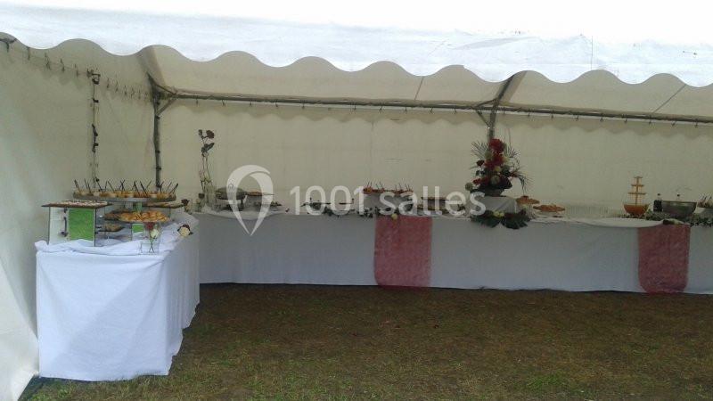 Buffet sous une tente blanche avec plats variés disposés sur des tables recouvertes de nappes blanches.