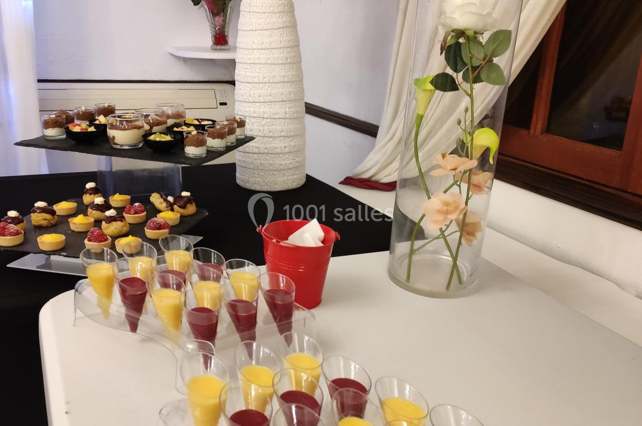 Desserts variés présentés sur une table, avec verrines colorées au premier plan et décor floral en arrière-plan.