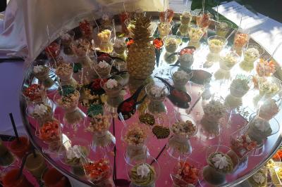 Salle de réception lumineuse avec tables dressées, chaises blanches, chandeliers et décorations florales.