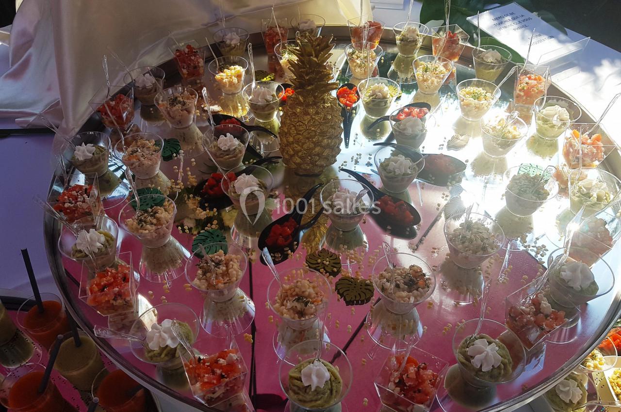Plateau circulaire avec verrines variées, décoré d'un ananas doré au centre, présenté sur une table.