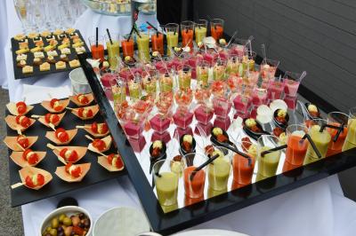 Salle de réception lumineuse avec tables dressées, chaises blanches, chandeliers et décorations florales.
