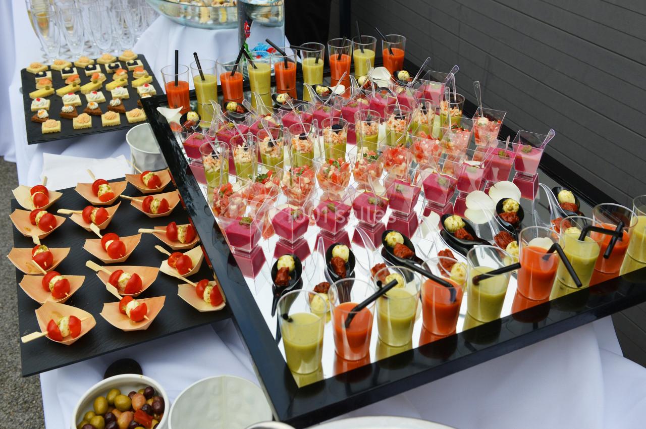 Plateau de verrines colorées et amuse-bouches variés disposés sur une table lors d'un buffet.