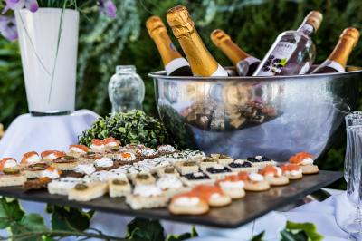 Salle de réception lumineuse avec tables dressées, chaises blanches, chandeliers et décorations florales.