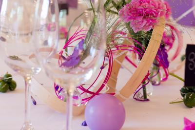 Salle de réception lumineuse avec tables dressées, chaises blanches, chandeliers et décorations florales.