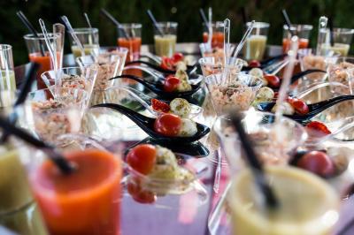 Salle de réception lumineuse avec tables dressées, chaises blanches, chandeliers et décorations florales.