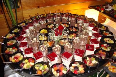 Salle de réception lumineuse avec tables dressées, chaises blanches, chandeliers et décorations florales.