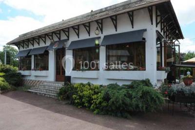 Salle de réception lumineuse avec tables dressées, chaises blanches, chandeliers et décorations florales.