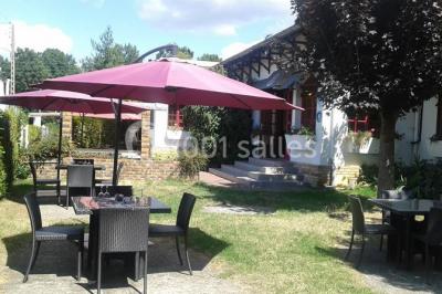 Salle de réception lumineuse avec tables dressées, chaises blanches, chandeliers et décorations florales.