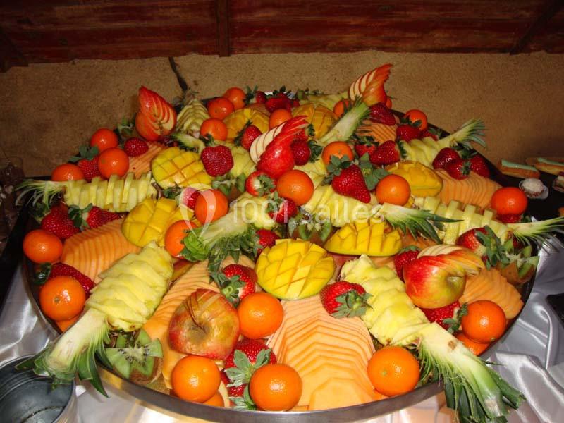 Plateau garni de fruits variés, incluant mangues, fraises, oranges, ananas et melon, disposés de manière décorative.