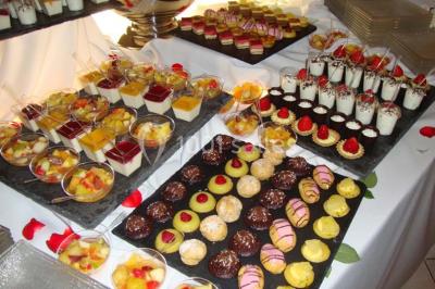 Salle de réception lumineuse avec tables dressées, chaises blanches, chandeliers et décorations florales.