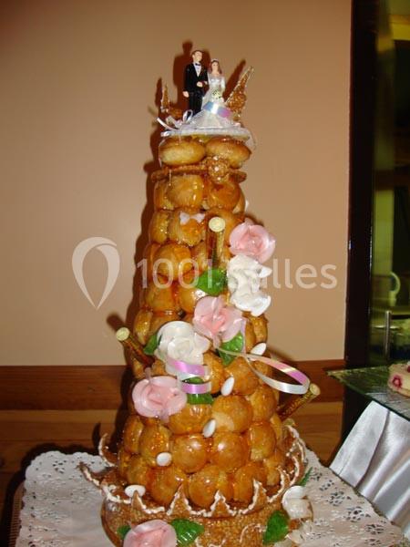 Pièce montée en choux garnie de décorations florales en sucre et figurines de mariés au sommet.