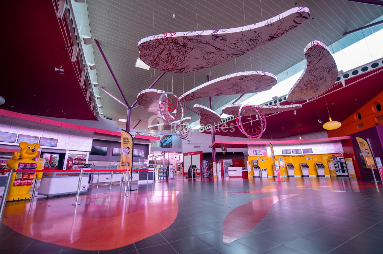 Vue intérieure d'un espace public coloré avec des guichets, des distributeurs automatiques et des décorations suspendues.