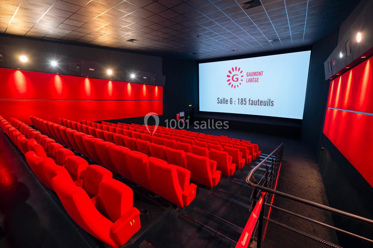 Salle de cinéma moderne avec rangées de fauteuils rouges et écran affichant ’Gaumont Labège, Salle 6 : 185 fauteuils’.