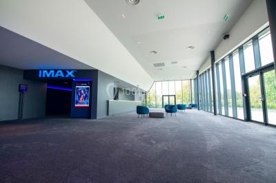Façade d'un cinéma Gaumont avec des affiches IMAX, un parvis vide et deux lampadaires au premier plan.