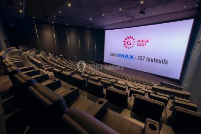 Façade d'un cinéma Gaumont avec des affiches IMAX, un parvis vide et deux lampadaires au premier plan.