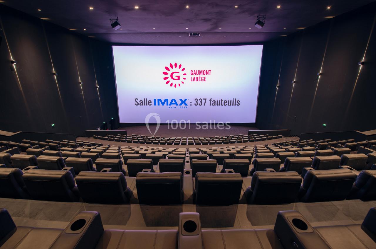 Salle de cinéma IMAX vide avec 337 fauteuils, écran géant et éclairage tamisé.