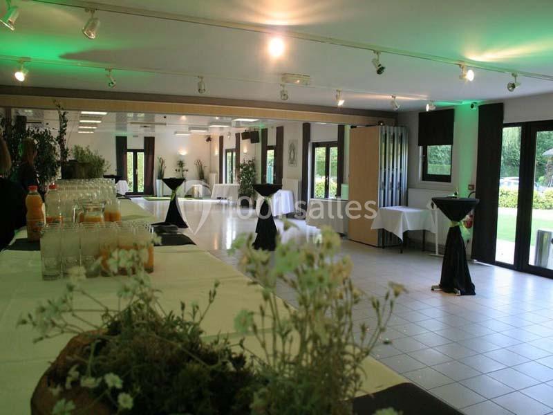 Salle lumineuse aménagée avec des tables dressées, des boissons et une vue sur l'extérieur verdoyant.