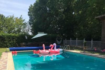 Façade d'une maison ancienne en pierre avec des fenêtres à petits carreaux, entourée de végétation.
