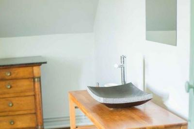 Façade d'une maison ancienne en pierre avec des fenêtres à petits carreaux, entourée de végétation.