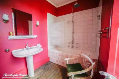 Façade d'une maison ancienne en pierre avec des fenêtres à petits carreaux, entourée de végétation.