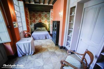Façade d'une maison ancienne en pierre avec des fenêtres à petits carreaux, entourée de végétation.