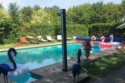 Façade d'une maison ancienne en pierre avec des fenêtres à petits carreaux, entourée de végétation.