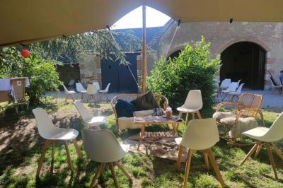 Façade d'une maison ancienne en pierre avec des fenêtres à petits carreaux, entourée de végétation.