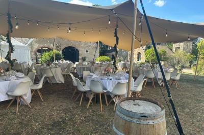 Façade d'une maison ancienne en pierre avec des fenêtres à petits carreaux, entourée de végétation.