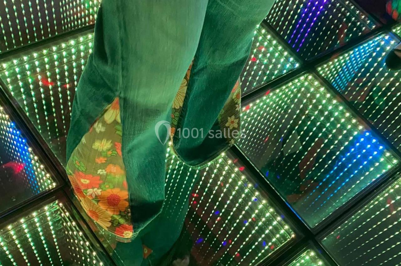 Pantalon en jean avec motifs floraux sur un sol lumineux à effet miroir infini.