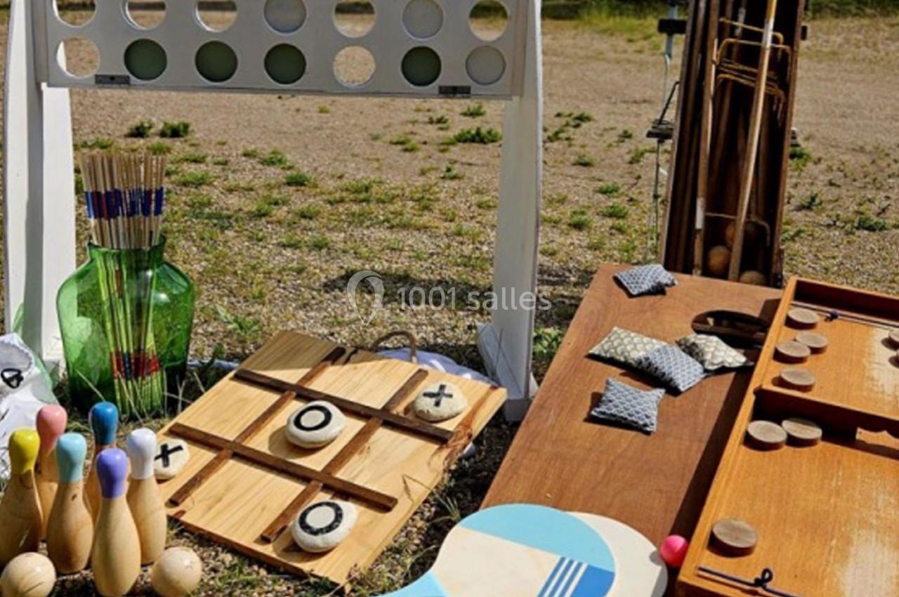 Jeux d'extérieur en bois, dont un morpion, des quilles, un jeu de palets et un jeu de lancer, disposés sur un sol…