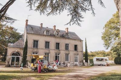 Façade d'une maison ancienne en pierre avec des fenêtres à petits carreaux, entourée de végétation.