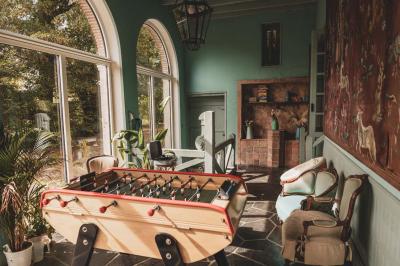 Façade d'une maison ancienne en pierre avec des fenêtres à petits carreaux, entourée de végétation.