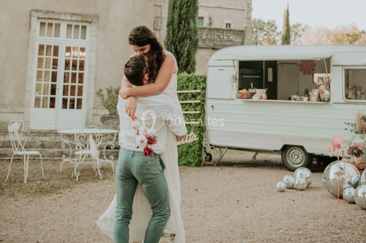Un couple danse en extérieur devant une caravane rétro, entouré de décorations festives et de mobilier de jardin.