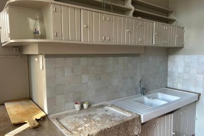 Façade d'une maison ancienne en pierre avec des fenêtres à petits carreaux, entourée de végétation.