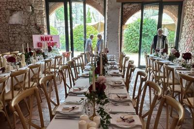 Façade d'une maison ancienne en pierre avec des fenêtres à petits carreaux, entourée de végétation.