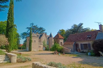 Façade d'une maison ancienne en pierre avec des fenêtres à petits carreaux, entourée de végétation.