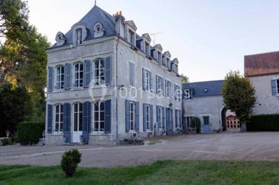 Façade d'un grand bâtiment ancien entouré de motos stationnées sur une pelouse et une allée gravillonnée.