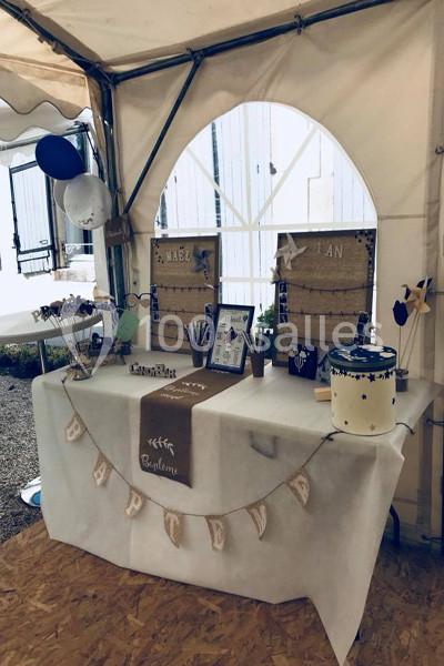 Table décorée pour un baptême avec guirlande, souvenirs, ballons et éléments personnalisés dans une tente.